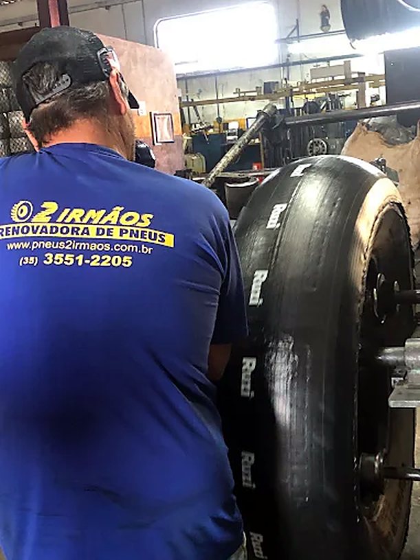 Colaborador com uniforme da Pneus 2 Irmãos aplicando a banda de rodagem